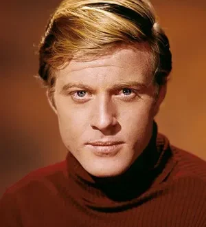 Foto in primo piano di Robert Redford che indossa un maglione marrone a collo alto su sfondo marrone più chiaro