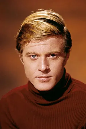 Foto in primo piano di Robert Redford che indossa un maglione marrone a collo alto su sfondo marrone più chiaro